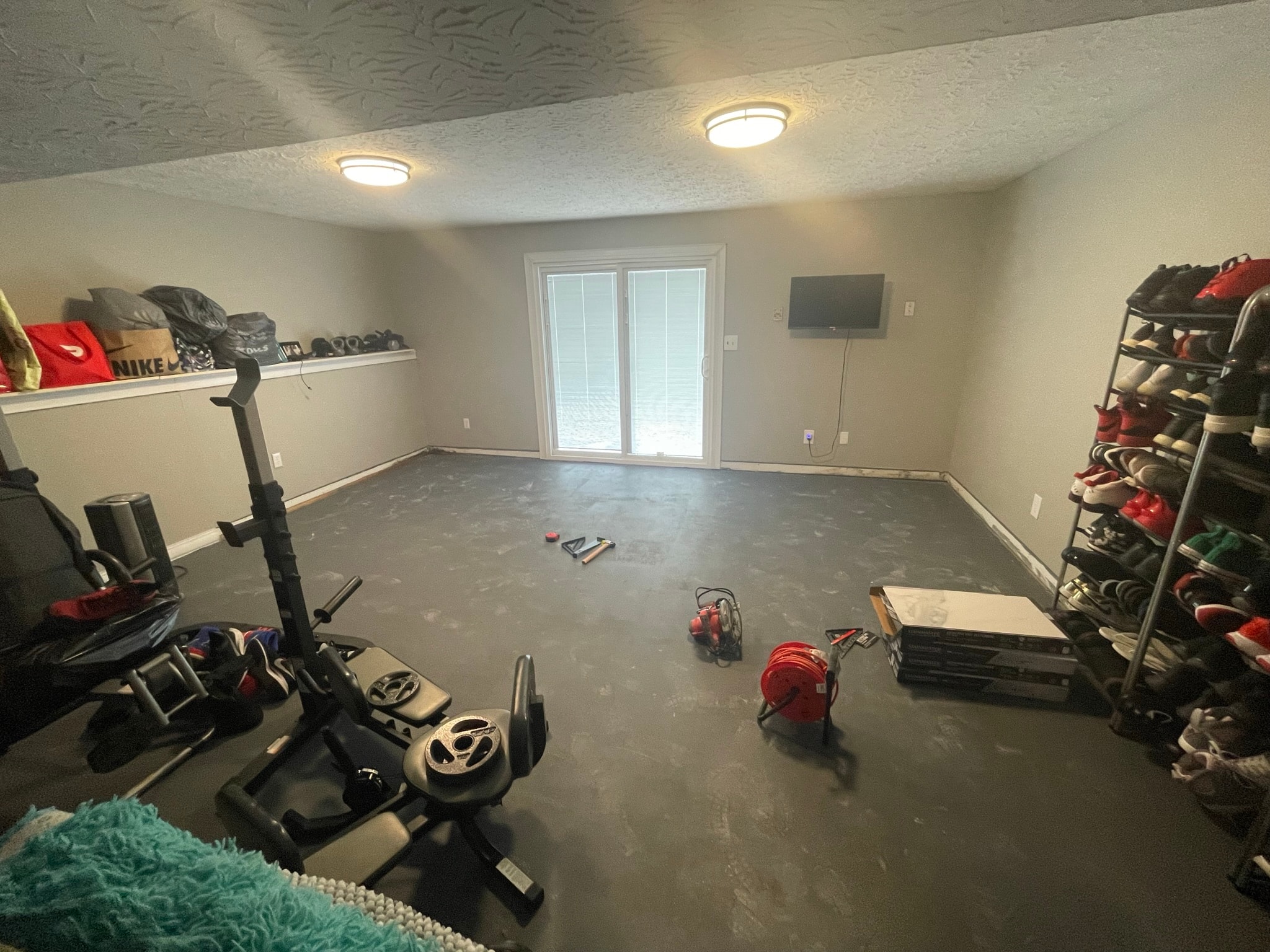 Basement before flooring installation — bare concrete floor with exercise equipment