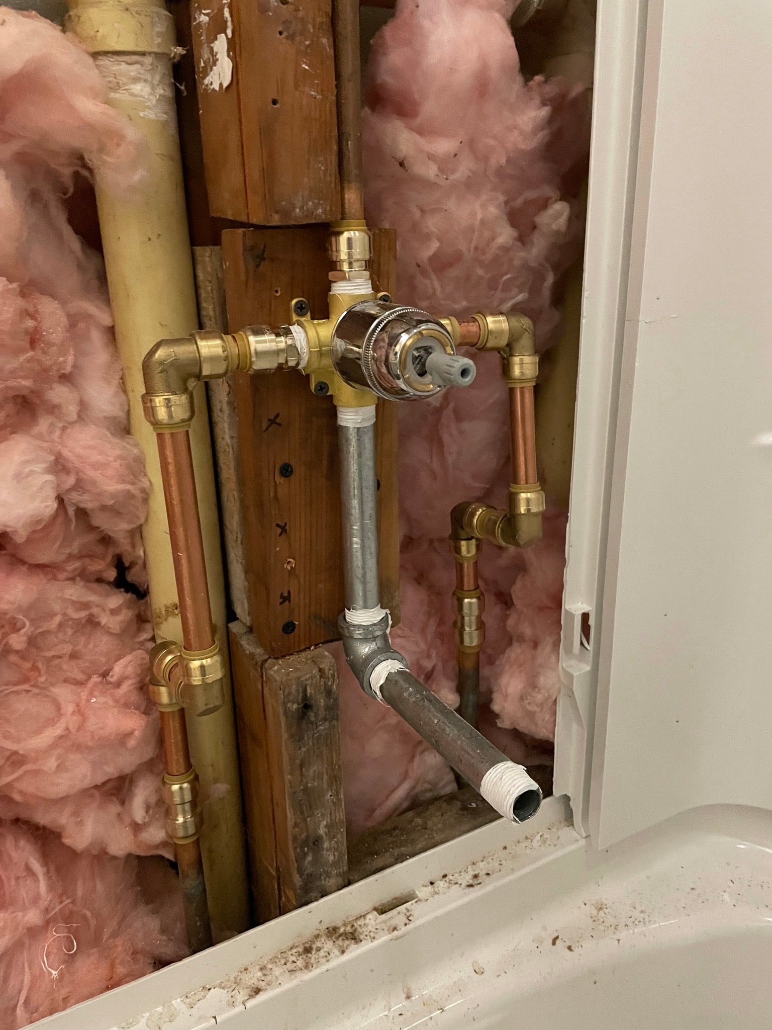 Plumbing after repair — new copper pipes, brass fittings, and pressure valve cleanly installed