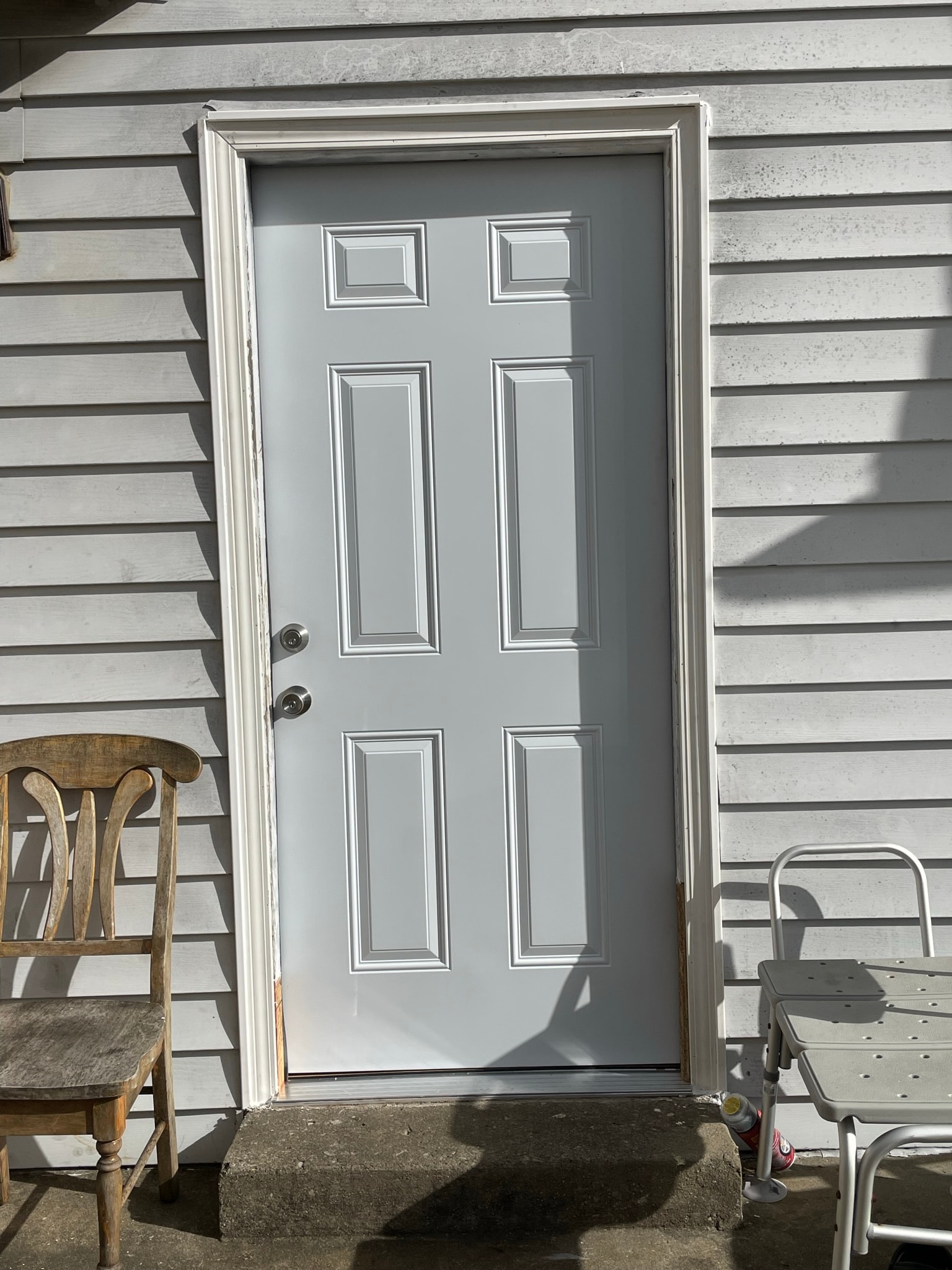 Exterior door after replacement — brand new 6-panel steel door with fresh paint and new hardware