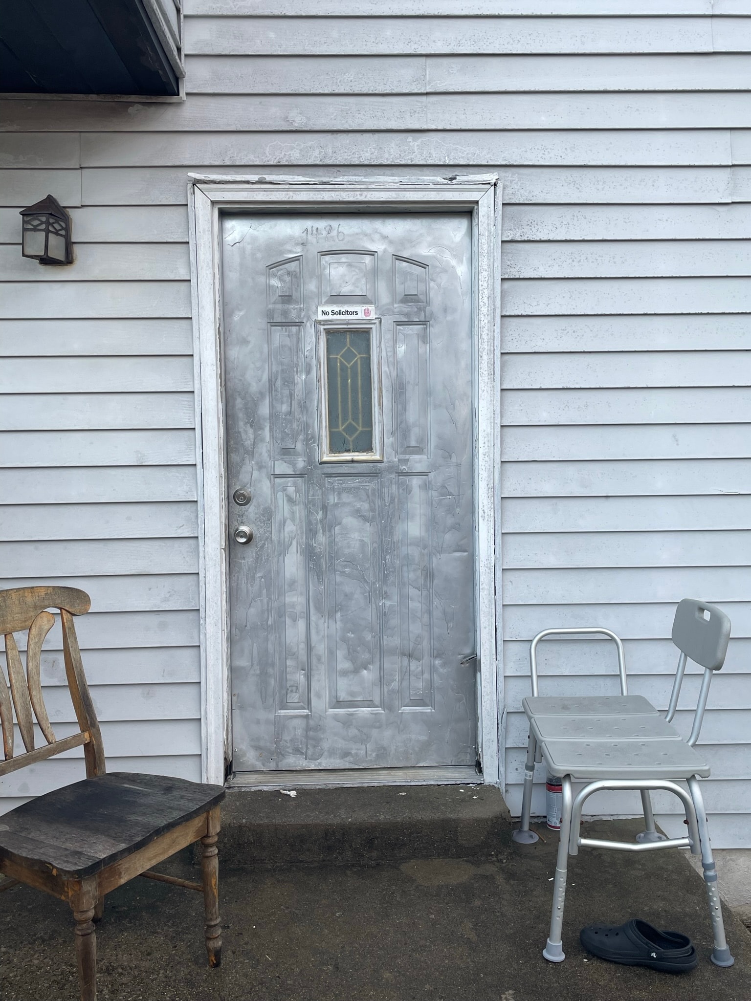 Exterior door before replacement — heavily scratched and weathered old door with peeling finish