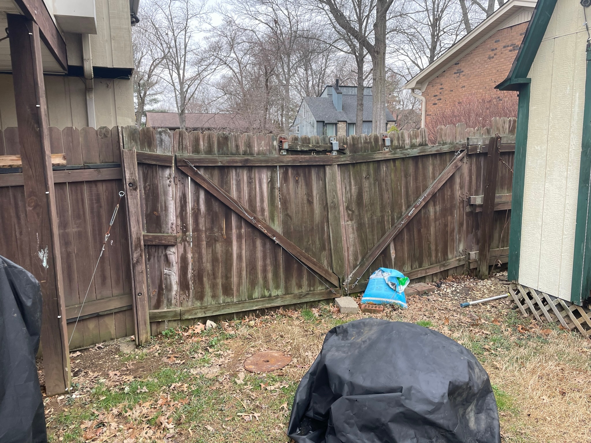 Backyard fence before replacement — rotting, moss-covered wooden gate and fence panels