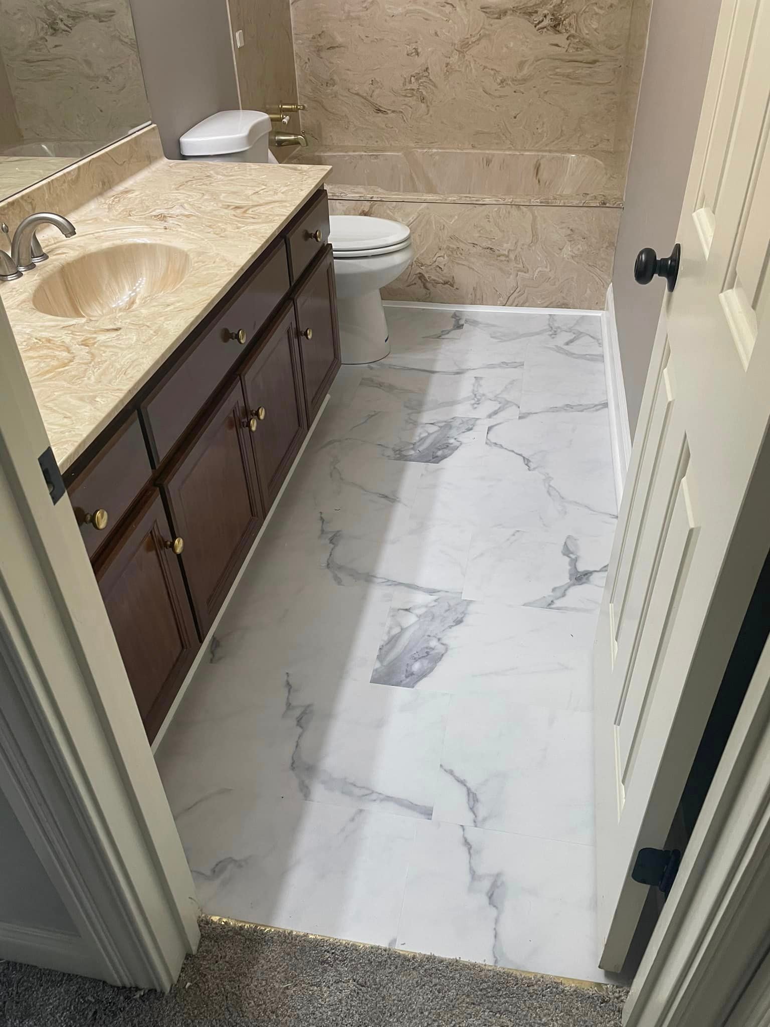 Bathroom floor after renovation — new large-format marble-look luxury vinyl tile with grey veining