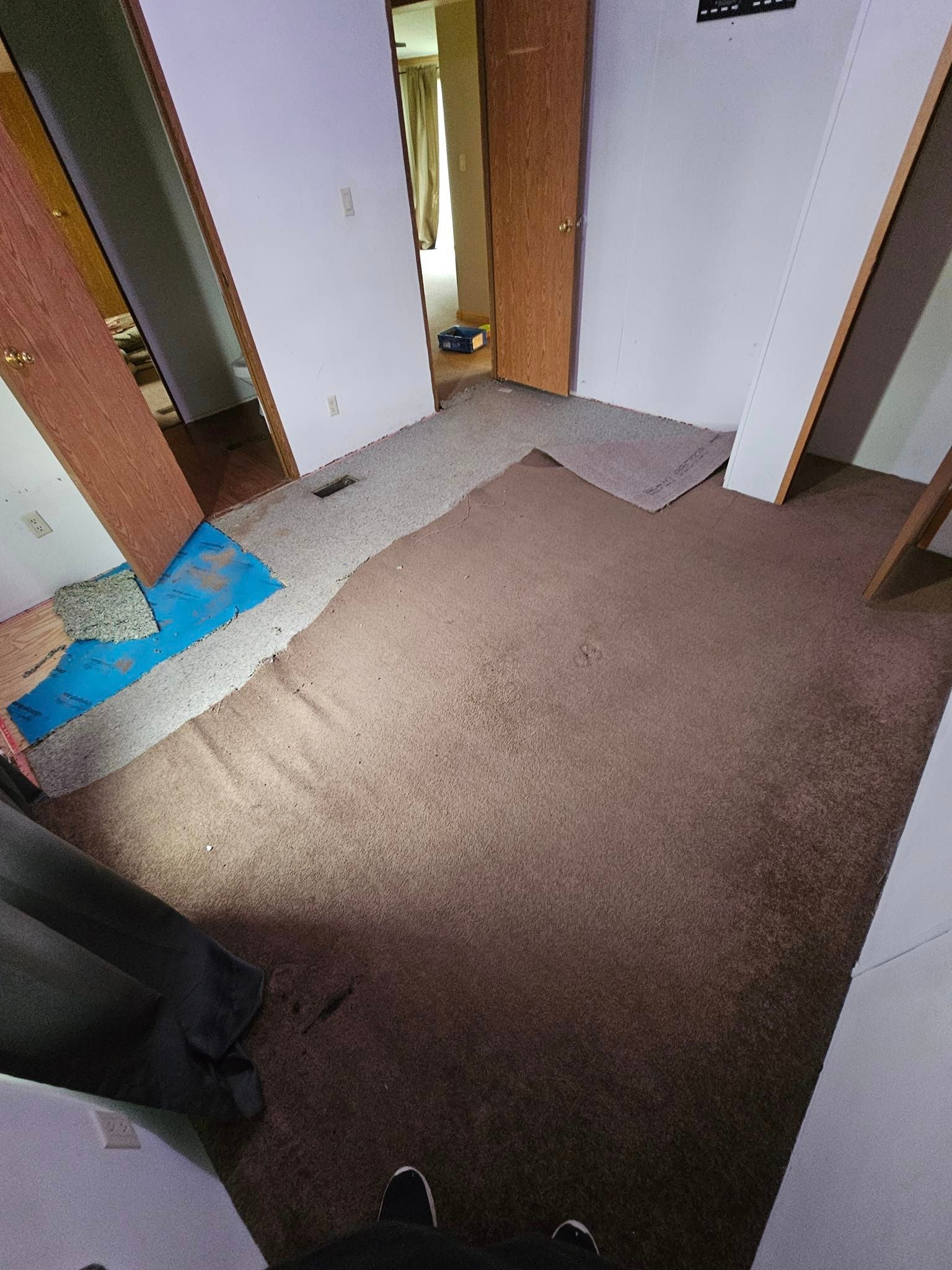 Bedroom before flooring renovation — old worn carpet being torn out with subfloor padding exposed