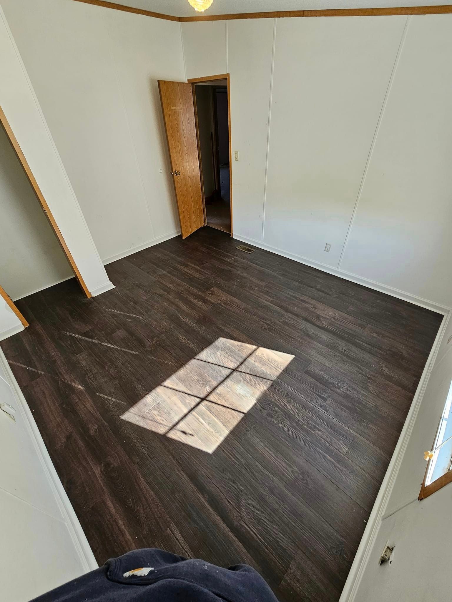 Bedroom after flooring renovation — rich dark espresso luxury vinyl plank flooring with natural light streaming in