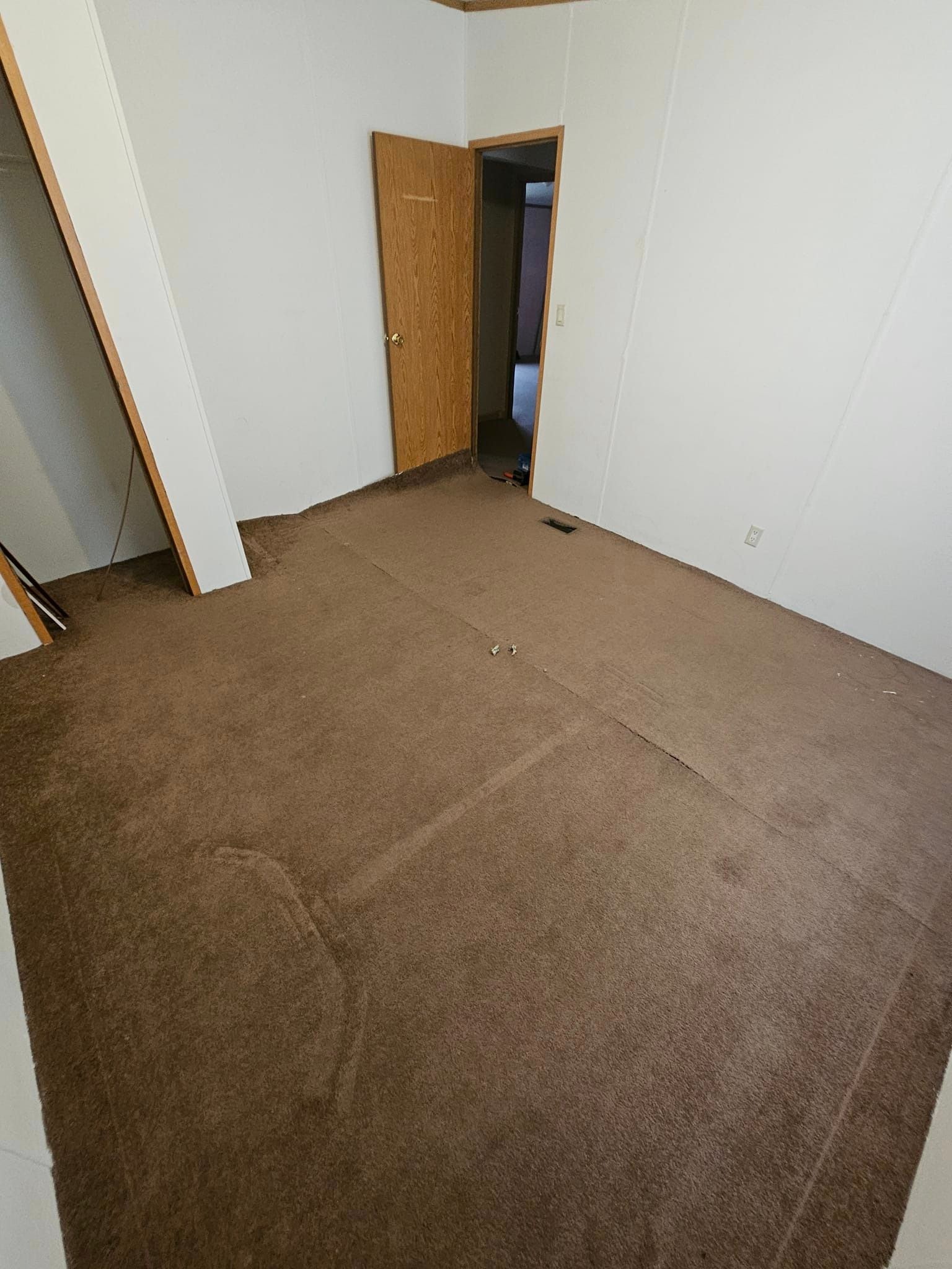 Bedroom before flooring renovation — worn brown carpet with visible seams and staining throughout