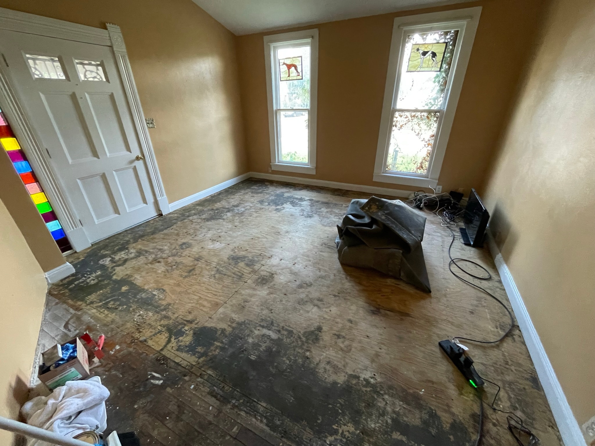 Living room before flooring — damaged subfloor with debris