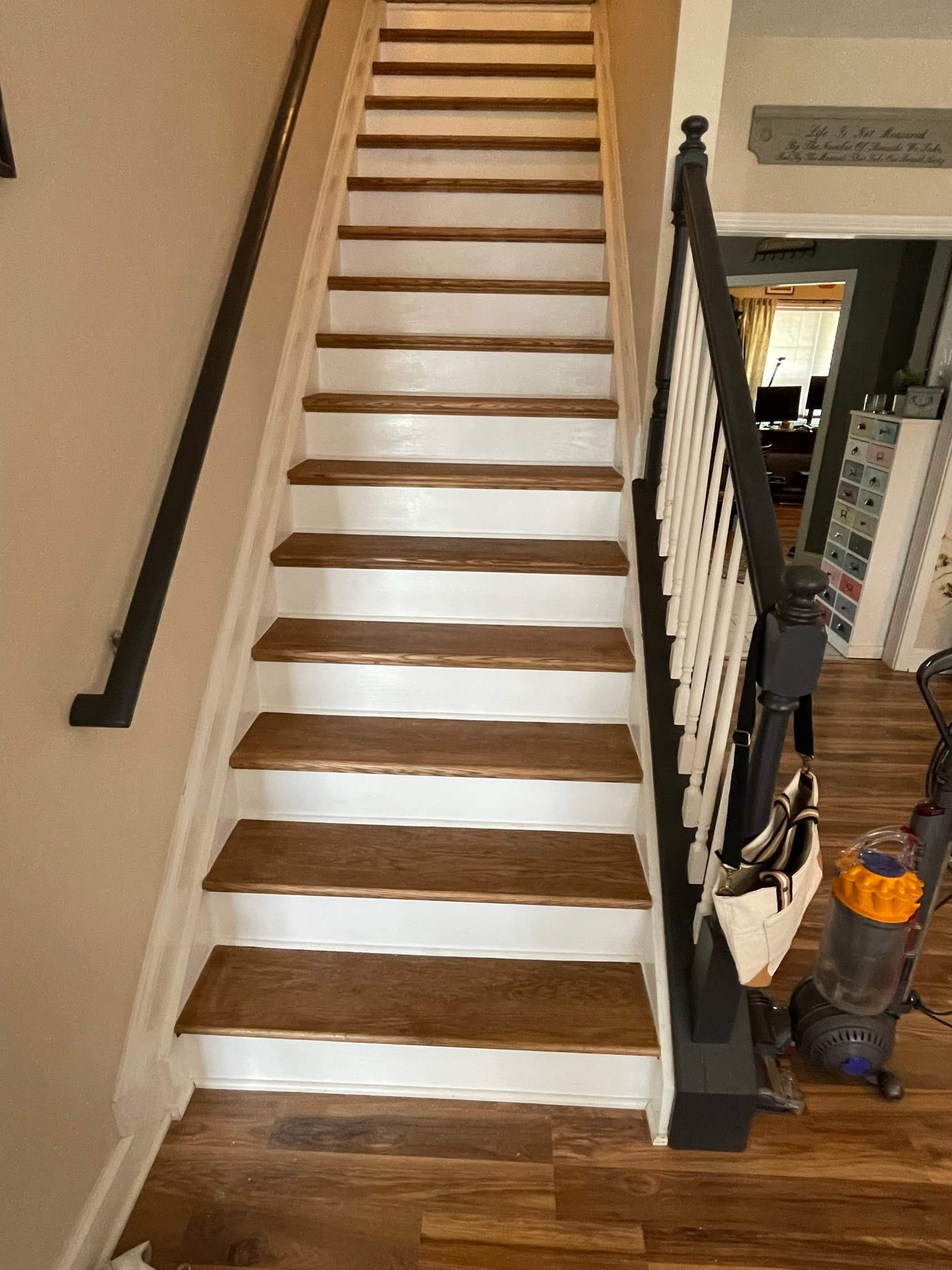 Interior staircase after tread replacement — uniform rich walnut stair treads with crisp white painted risers and black spindle railing