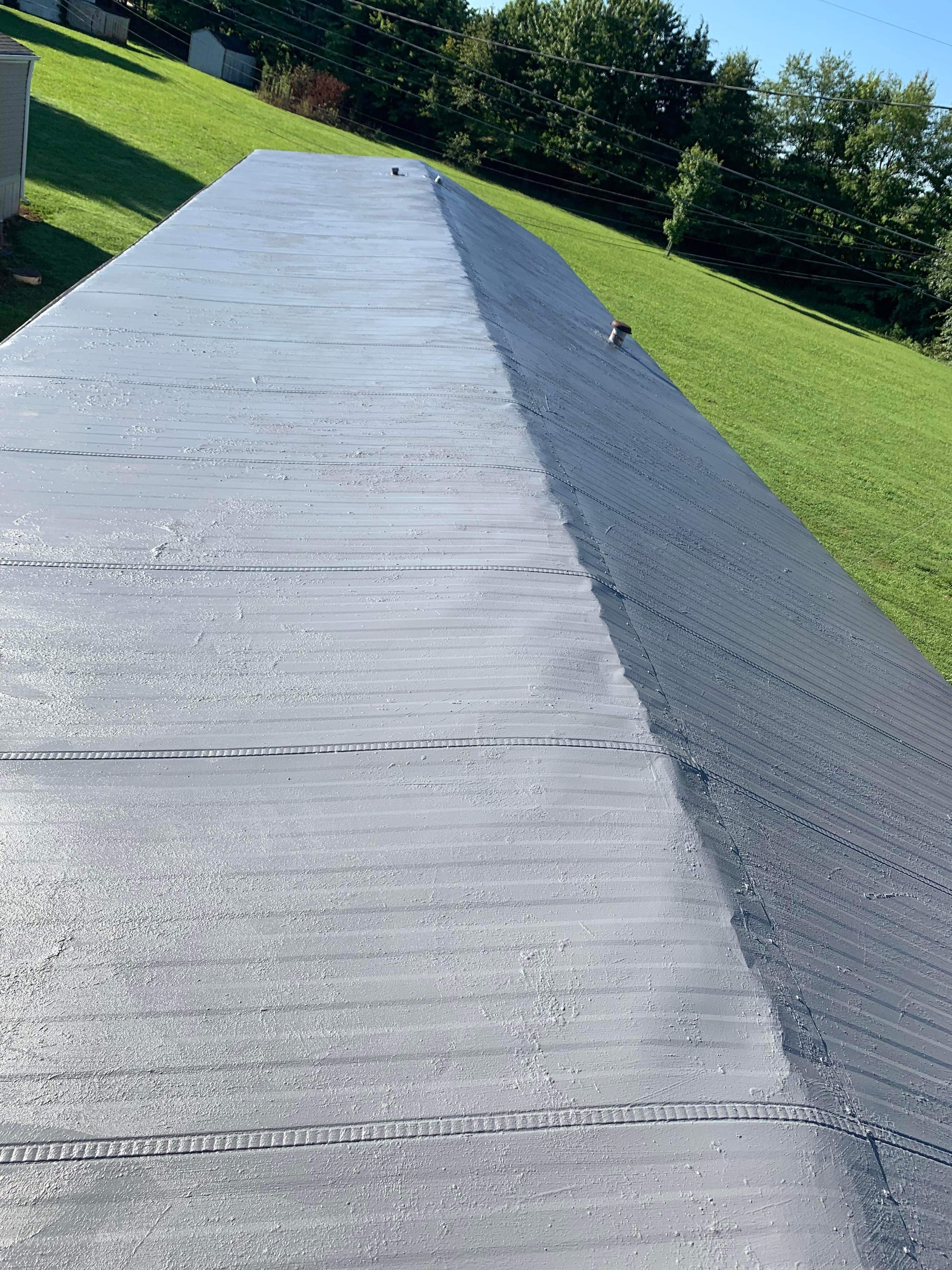 Mobile home metal roof after coating — same roof now fully covered in a clean uniform silver elastomeric roof coating with no rust visible