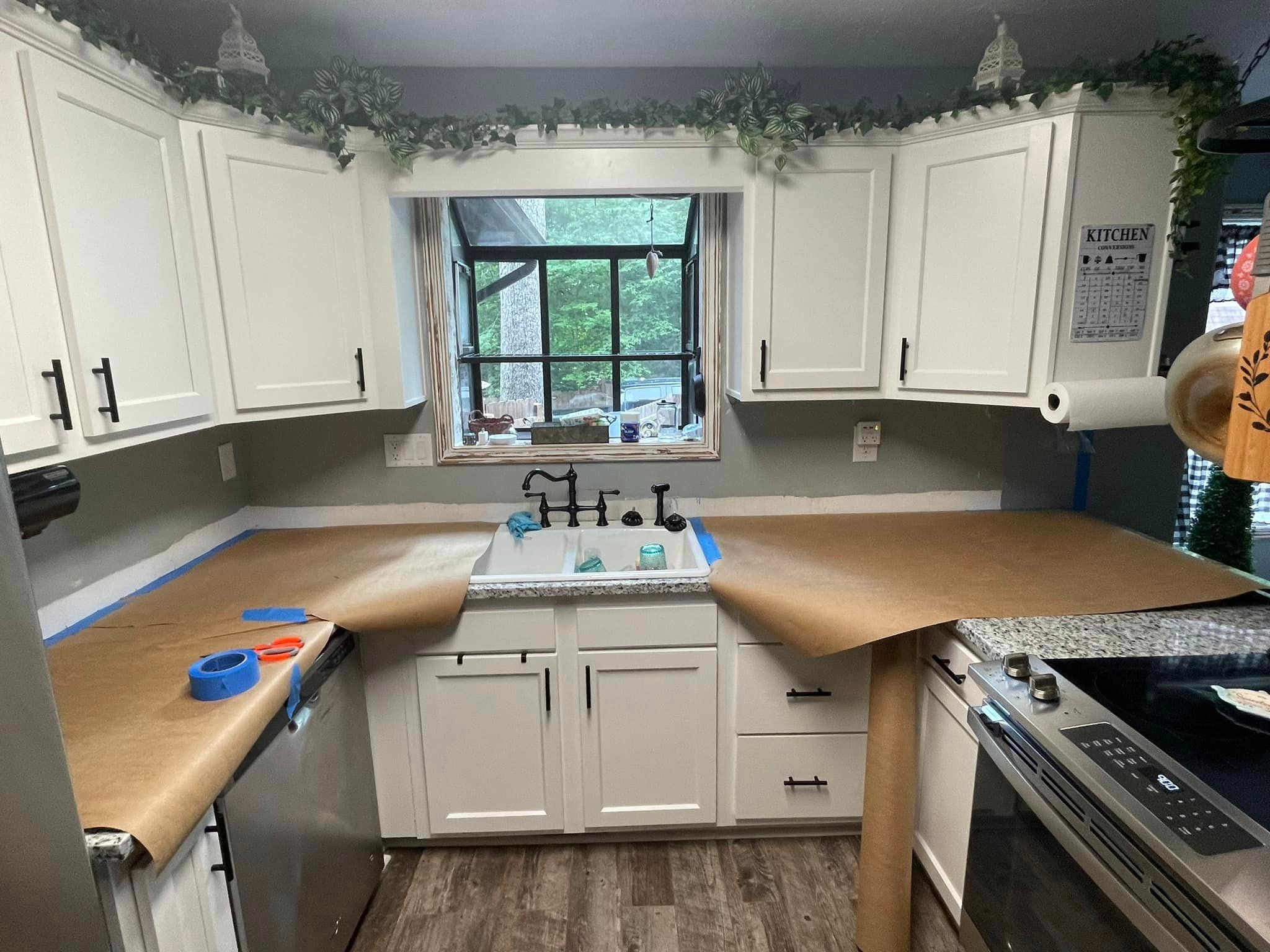 Kitchen before renovation — countertops covered with paper and blue tape during prep