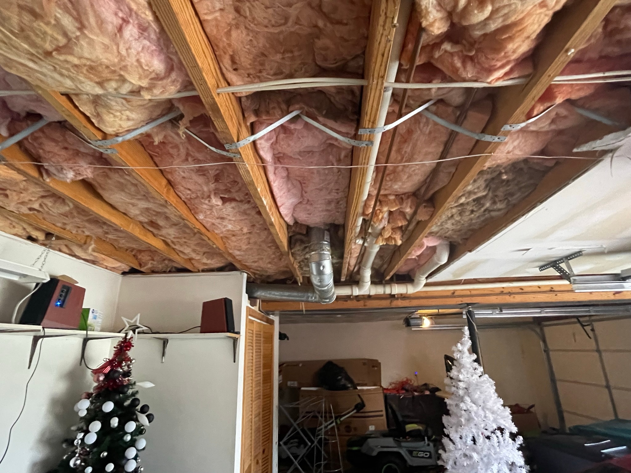 Garage ceiling before drywall — exposed insulation and framing