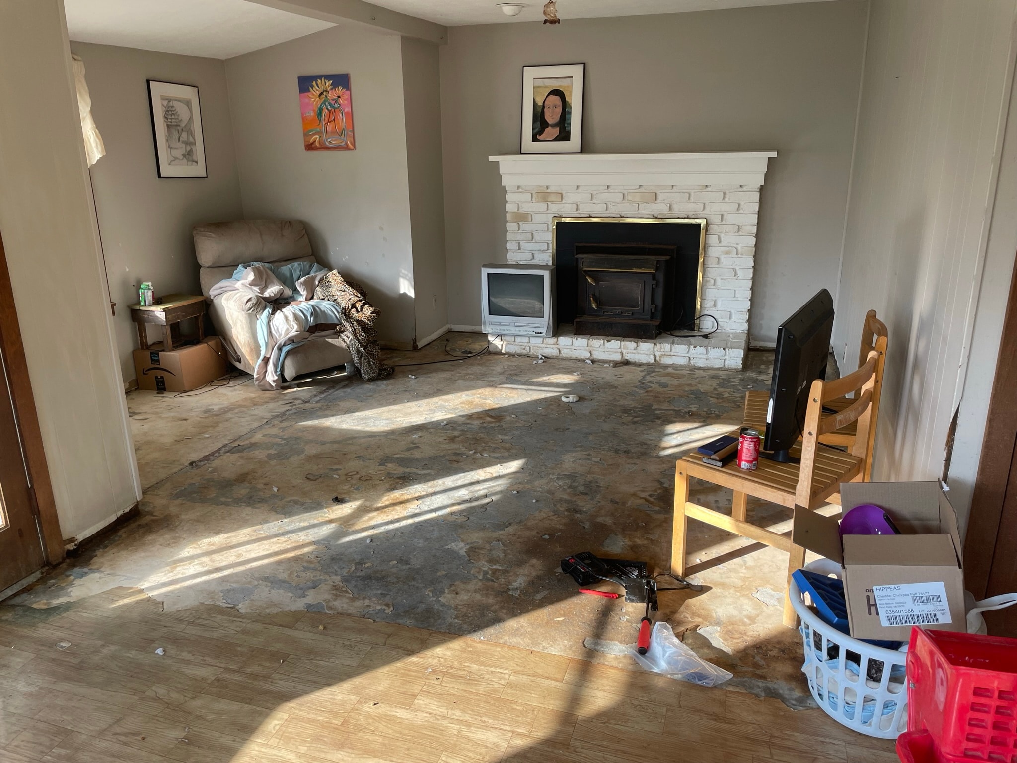 Living room before flooring — damaged subfloor with debris and old furniture