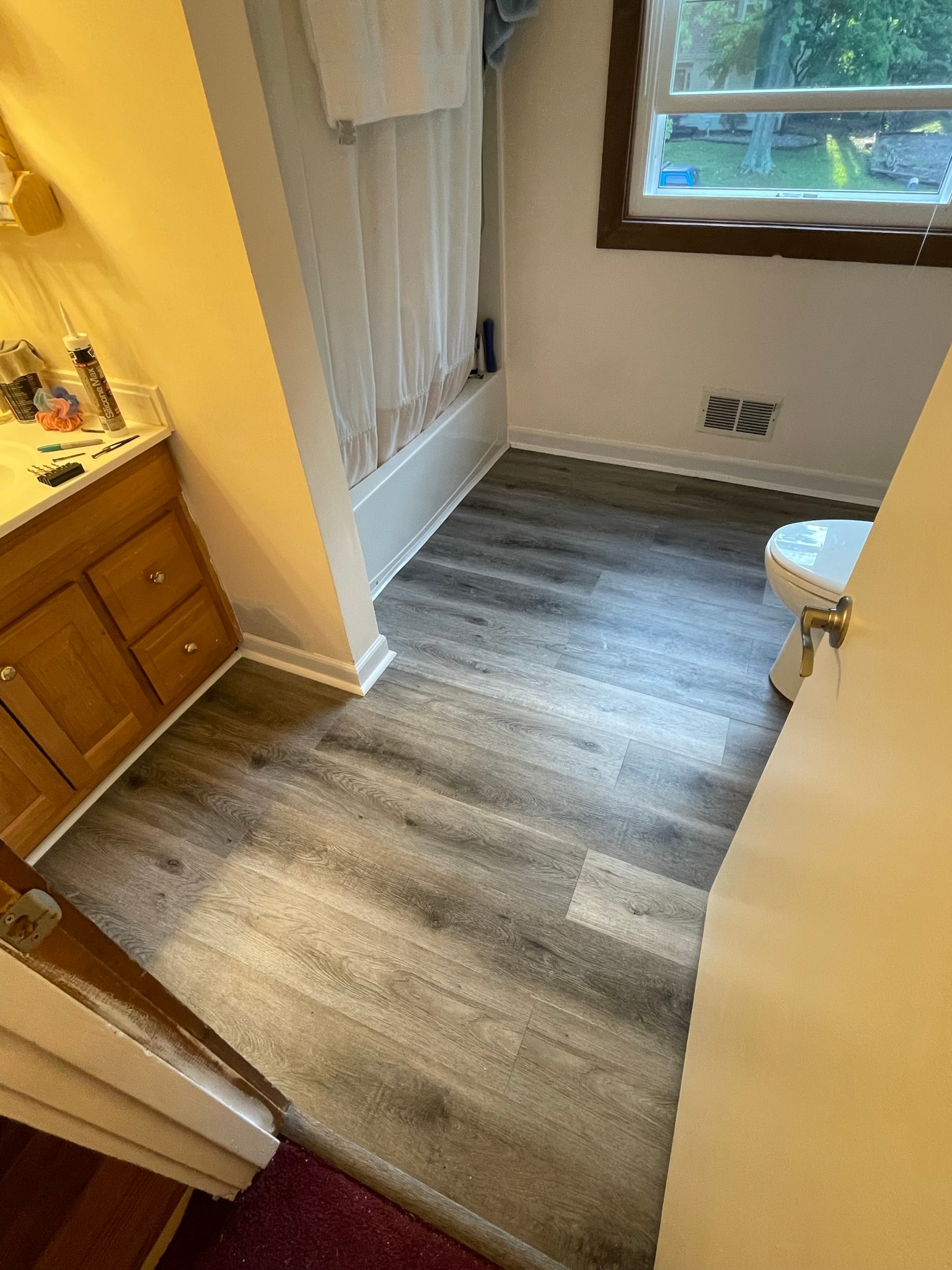 Bathroom after flooring — fresh grey luxury vinyl plank installation