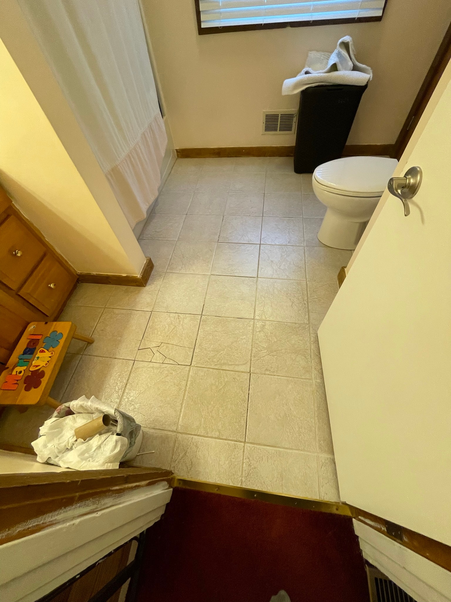 Bathroom before flooring — cracked and worn tile floor