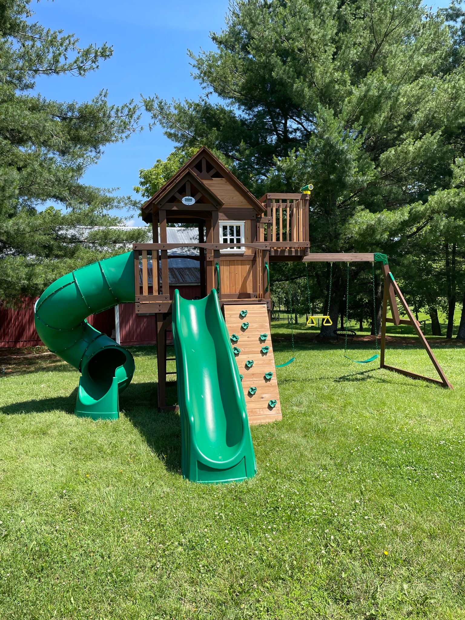 Playground set fully assembled — two-story playset with green slides, rock wall, swings, and tube slide